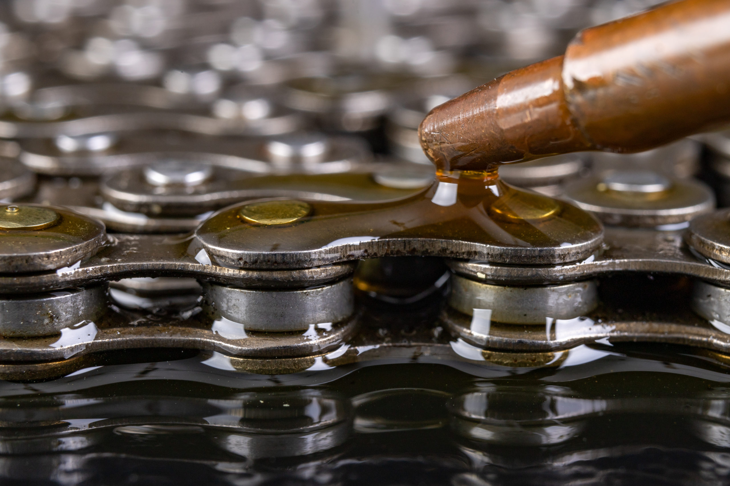 Lubricating the bicycle chain with oil from the oil can. Maintenance activities of bicycle gears. Dark background.